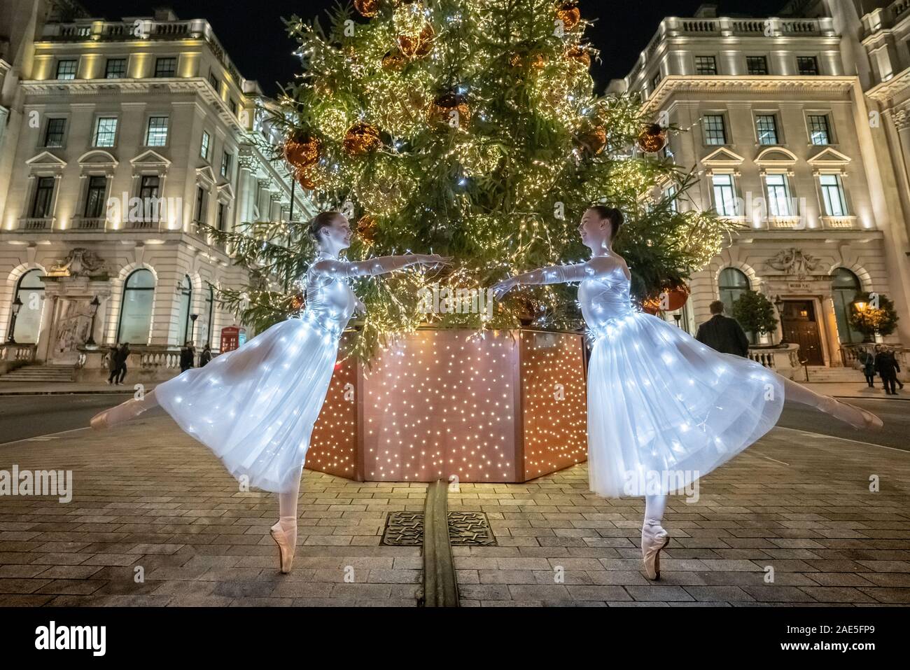 London, Großbritannien. 6. Dezember, 2019. Tänzer aus Semaphore Ballet Company durchführen, beleuchtete Fairy leichte Kleider neben St James's Weihnachtsbaum auf dem unteren Regent Street. Tänzer (L-R) Amy Davies und Jasmin Koch. Credit: Guy Corbishley/Alamy leben Nachrichten Stockfoto