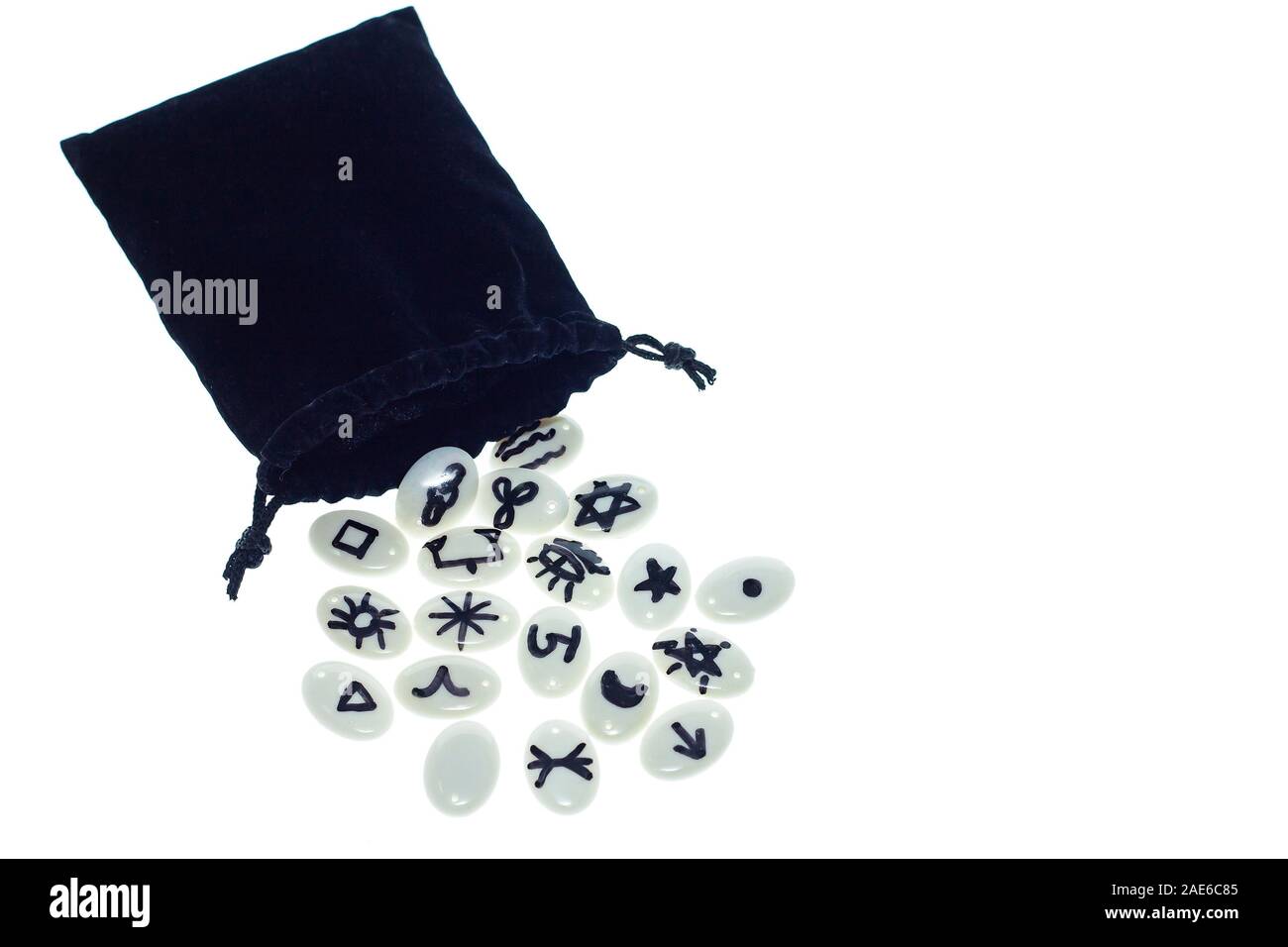 Satz von weißem Opal Runen in einem schwarzen Beutel auf weißem Hintergrund Stockfoto