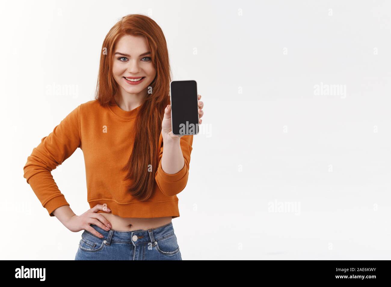 Attraktive moderne redhead Hipster girl in 7/8-Pullover smartphone Anwendung fördern, kaufen Gerät. Lächelnde Frau mit mobilen Bildschirm als Beratung Stockfoto