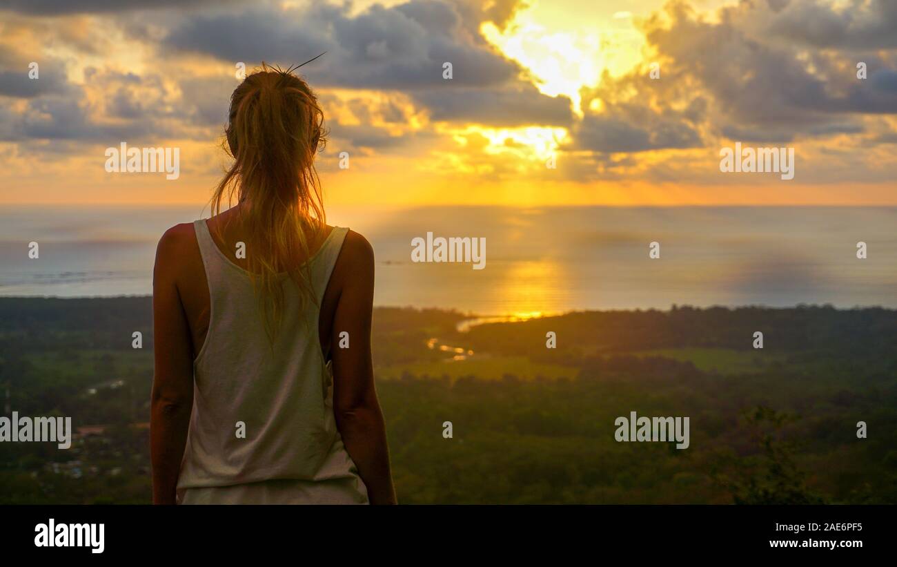 Inspirierende Szene einer Frau, die in der Sicht der Suche direkt auf den pazifischen Ozean während einer atemberaubenden Sonnenuntergang, Himmel bunt. Stockfoto