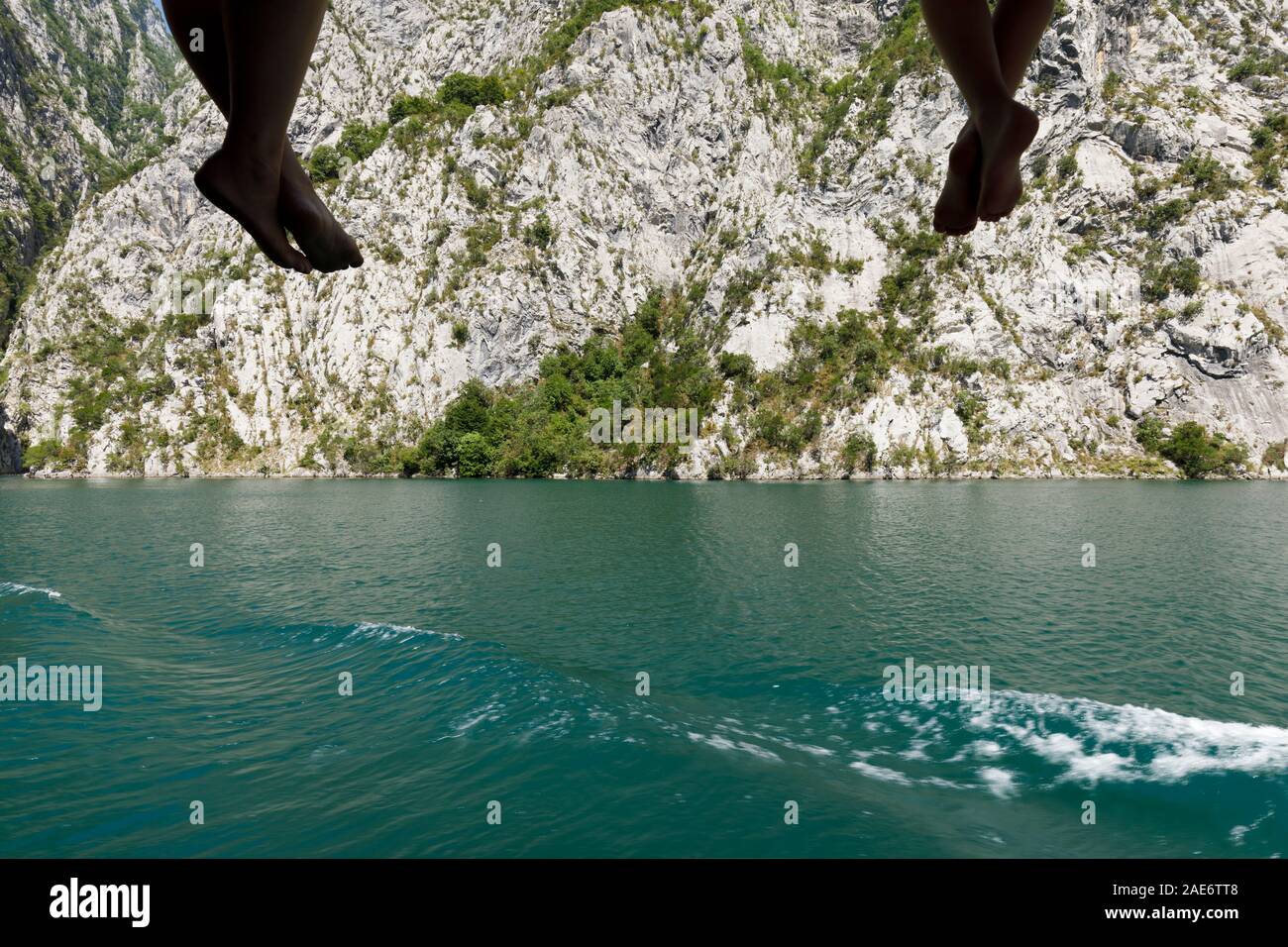 Nahaufnahme der Passagiere ihre Beine und Füße baumeln von der Reling und geniessen Sie die herrliche Landschaft auf der Komani See, Albanien Stockfoto