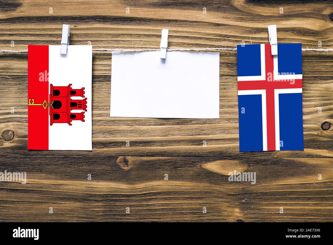 Hängenden Flaggen von Gibraltar Island und Seil mit wäscheklammer mit Kopie Raum befestigt auf weißem Papier auf Holz- Hintergrund. diplomatischen Beziehungen Stockfoto