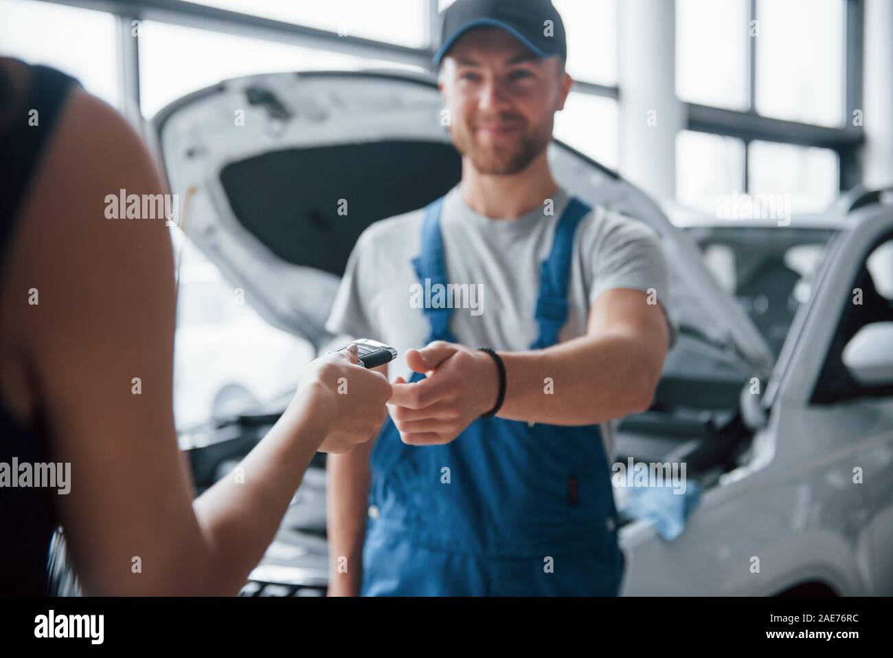 Keine Sorge, alles in Ordnung sein wird. Frau im Auto Salon mit Mitarbeiter in der blauen Uniform, Ihrem reparierten Auto zurück Stockfoto