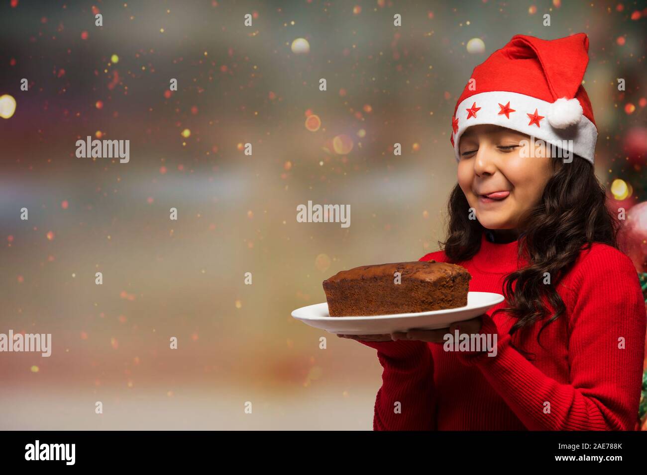 Junges Mädchen mit einem leckeren Teller rum Kuchen in der Hand während der Weihnachtszeit. Stockfoto