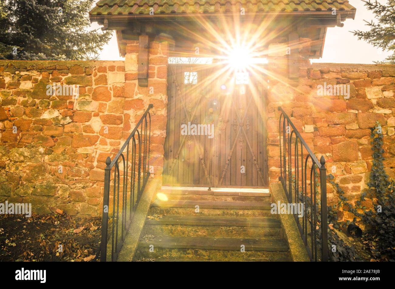 Steinmauer mit Holz alte Tür und Sonnenstrahlen durchscheinen. Konzept von Heaven's Gate Stockfoto