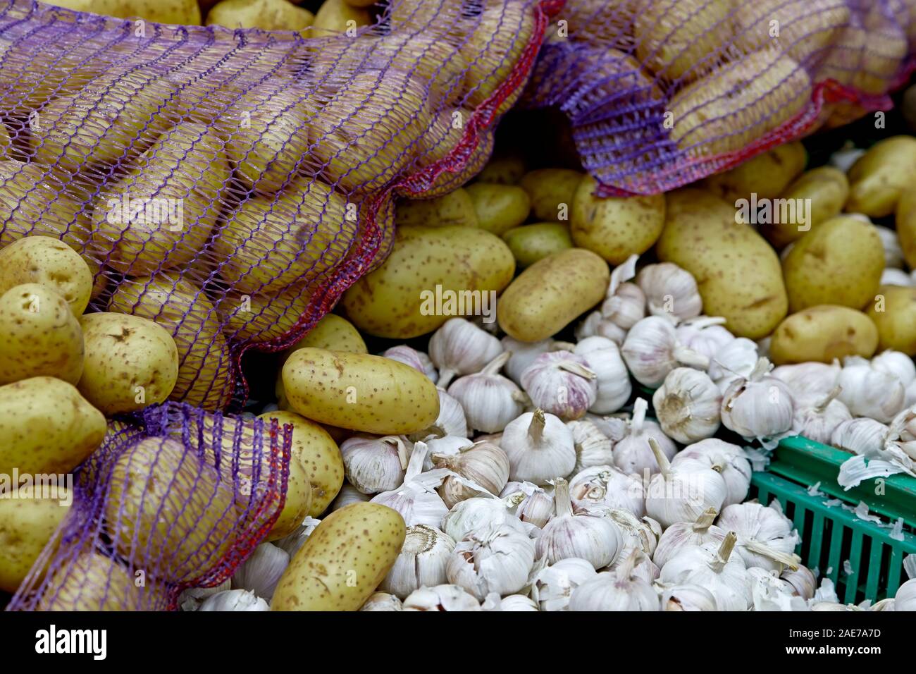 Gemüse der Saison werden in Kartons im Lebensmittelgeschäft gestapelt. In der Nähe liegen große Knollen Kartoffeln und Knoblauch. Ökologische Lebensmittel. Stockfoto