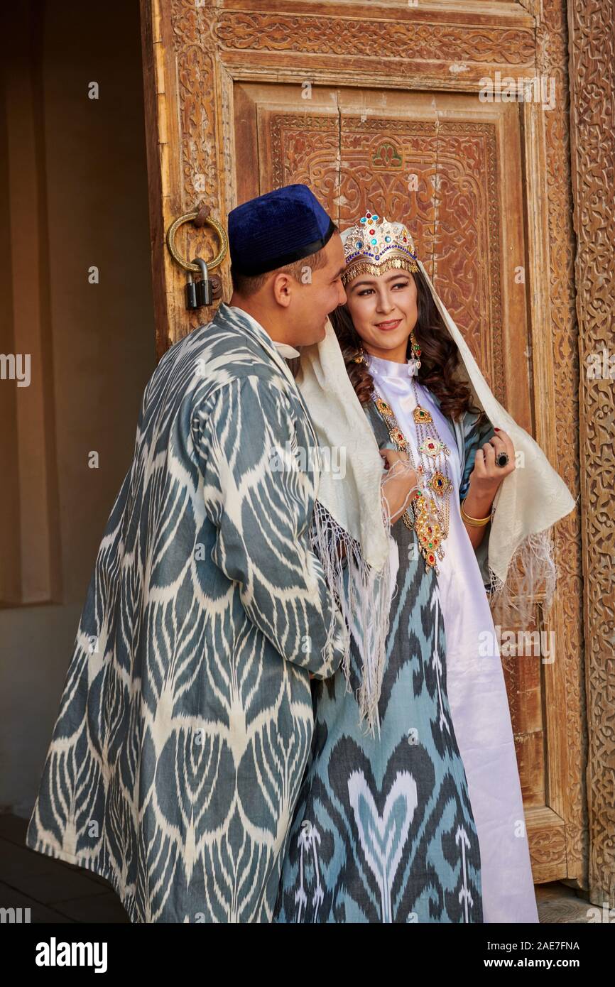 Brautpaar in traditioneller Kleidung vor der berühmten Registan Platz, Samarkand, Usbekistan, in Zentralasien posing Stockfoto