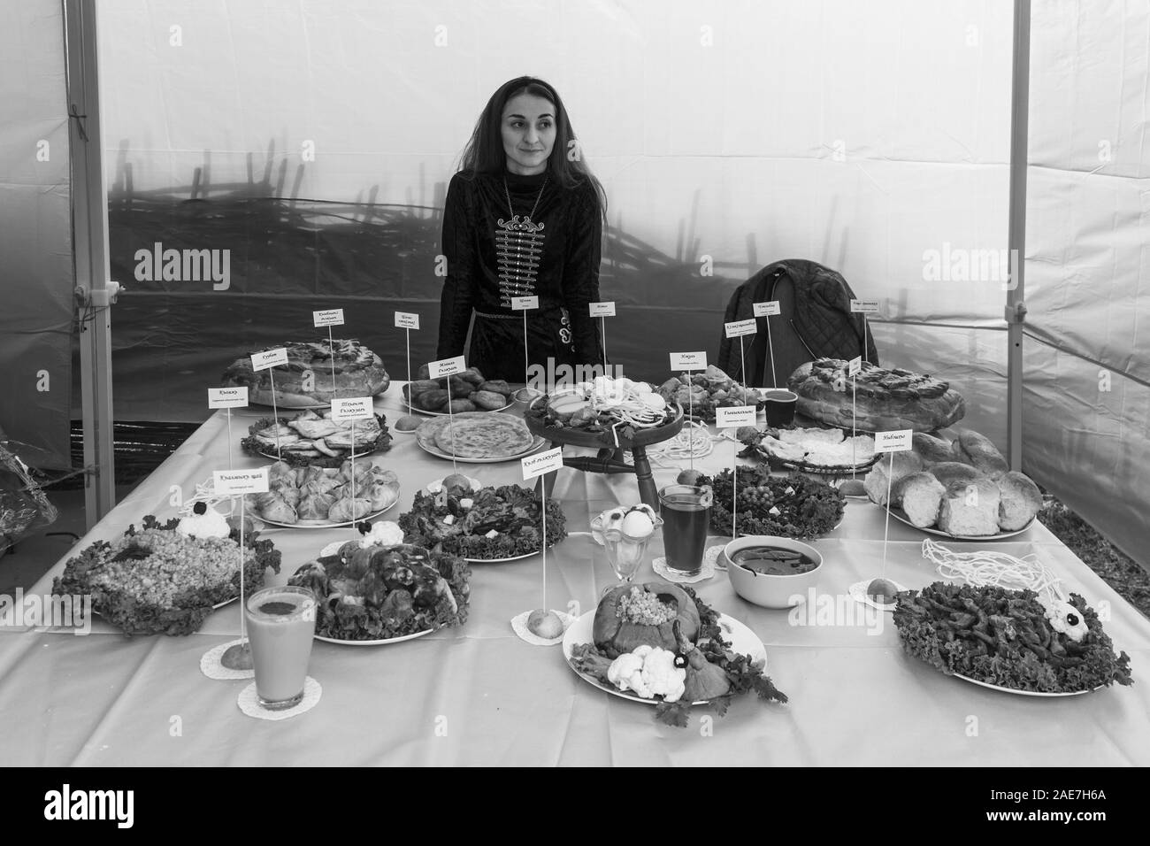 Adygea, Russland - September 21, 2019: junge Adyghe Mädchen und verschiedene Gerichte von Adyghe Küche auf dem Festival von Adyghe Käse, Schwarz und Weiß Foto Stockfoto