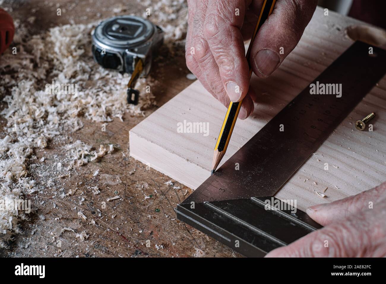 Tischler Messungen auf einem Tisch mit einem Bleistift und einem Metall Square Stockfoto