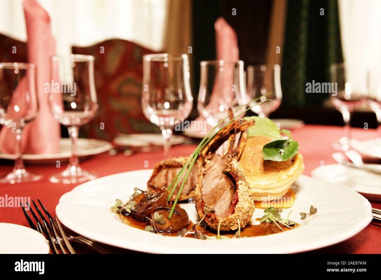 Lammkarree mit karamellisierten Zwiebeln und hausgemachten Brötchen am Tisch im Restaurant, getönt Stockfoto