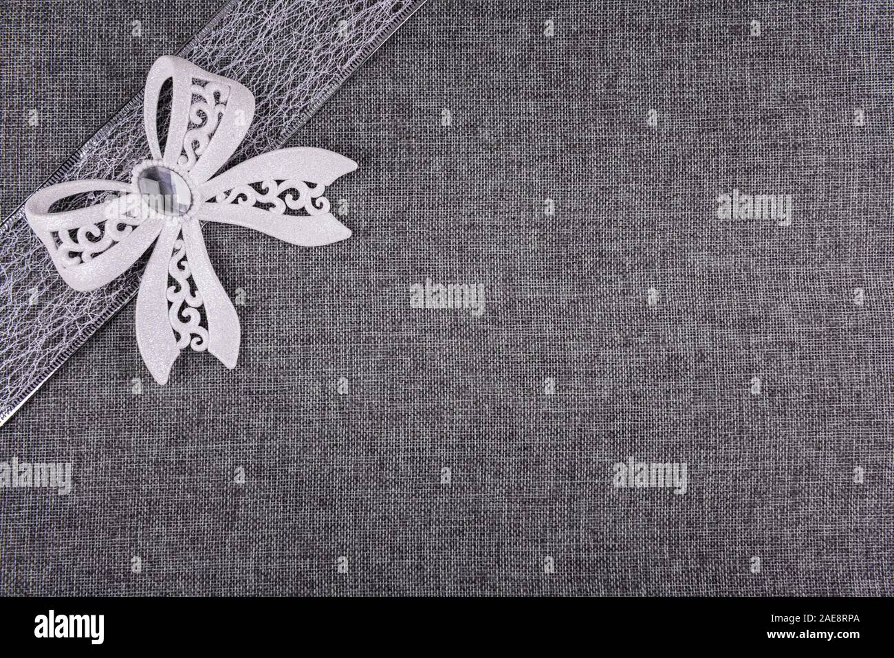 Elegante gebunden weiß glitter Bug auf Silber Farbband und auf Grau sackleinen. Horizontale Grußkarte Hintergrund mit großen Kopie Raum und Deco Stockfoto