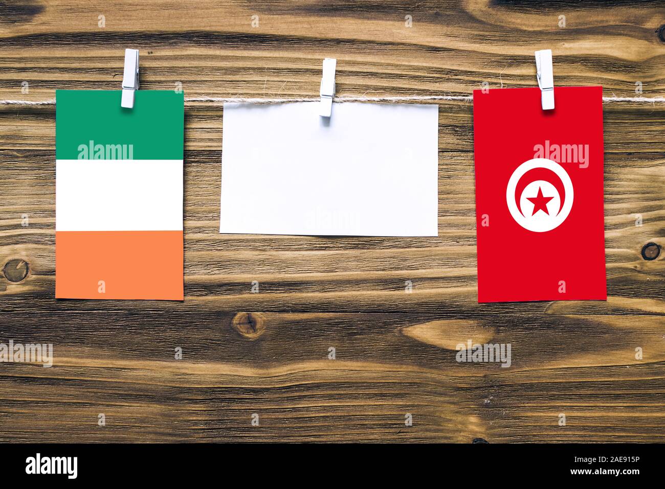 Hängende Fahnen von Irland und Tunesien, Seil mit wäscheklammer mit Kopie Raum befestigt auf weißem Papier auf Holz- Hintergrund. Diplomatische Beziehungen Stockfoto