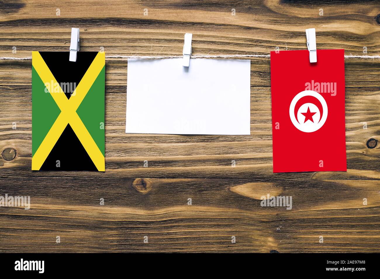 Hängenden Flaggen von Jamaika und Tunesien, Seil mit wäscheklammer mit Kopie Raum befestigt auf weißem Papier auf Holz- Hintergrund. Diplomatische Beziehungen Stockfoto