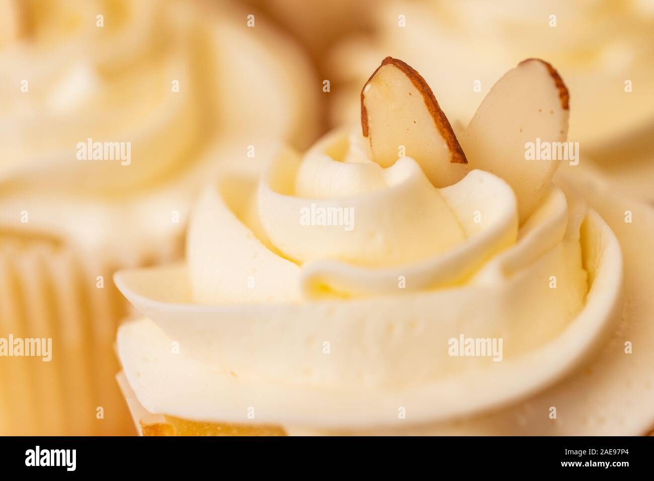 Zwei Mandelblättchen thront auf einem Cupcake mit weißer Zuckerglasur. Stockfoto