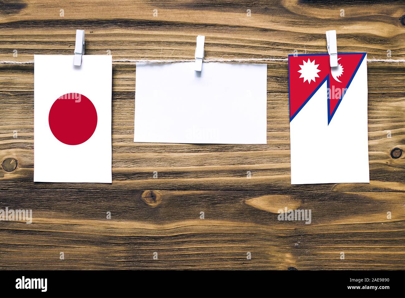 Hängenden Flaggen von Japan und Nepal zu Seil mit wäscheklammer mit Kopie Raum befestigt auf weißem Papier auf Holz- Hintergrund. Diplomatische Beziehungen zw. Stockfoto