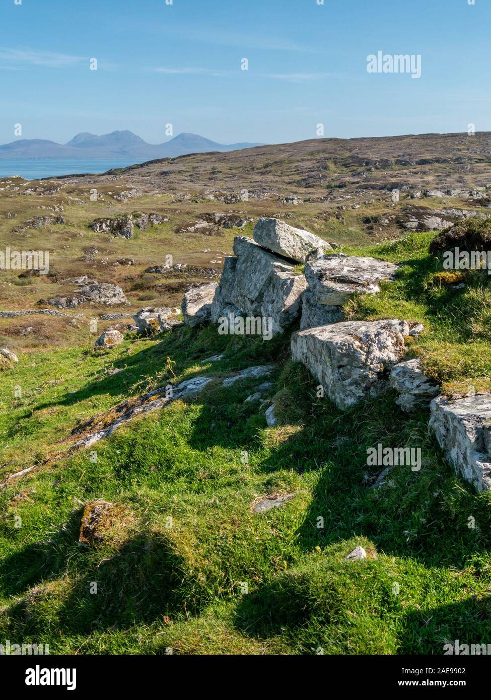 Die Reste der alten Bergfestung Steinmauer, Dun Cholla auf der Insel Colonsay mit der Paps Jura in der Ferne, Schottland, Großbritannien. Stockfoto