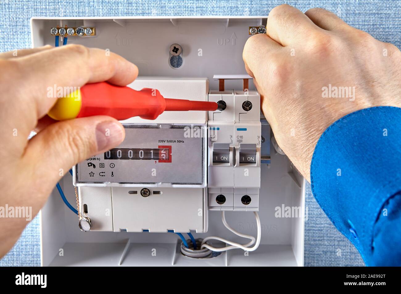 Verbraucher mit elektrischer oder Energiezähler und Leistungsschalter. Ein Elektriker mounts automatische Sicherungen, die Anbindung über die Schiene. Stockfoto