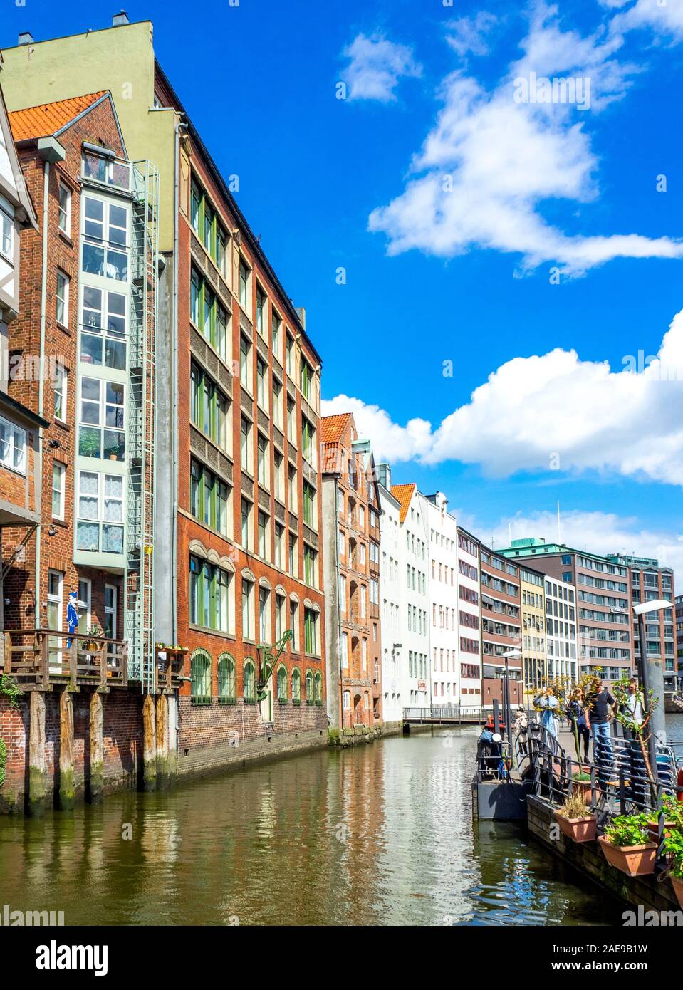 Touristen, die auf dem Ponton auf dem Nikolaifleet auf dem Gehweg spazieren und die Wohnungs- und Bürogebäude am Wasser in der Altstadt Hamburg betrachten Stockfoto