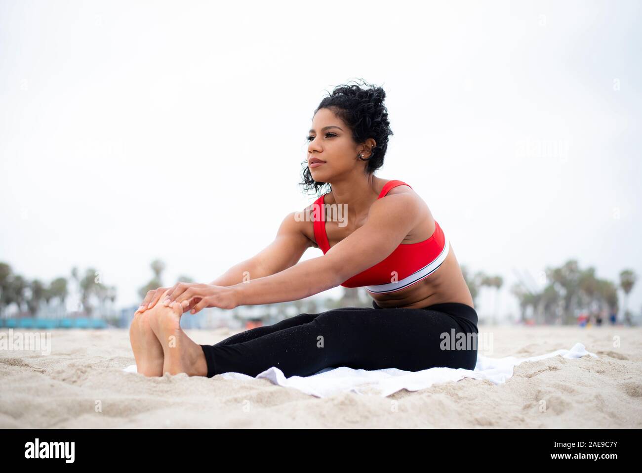 Physikalisch-fit-latina erstreckt sich am Strand vor dem Training Stockfoto