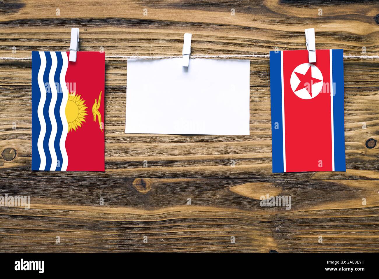 Hängende Fahnen von Kiribati und Nordkorea zu Seil mit wäscheklammer mit Kopie Raum befestigt auf weißem Papier auf Holz- Hintergrund. Diplomatischen relat Stockfoto