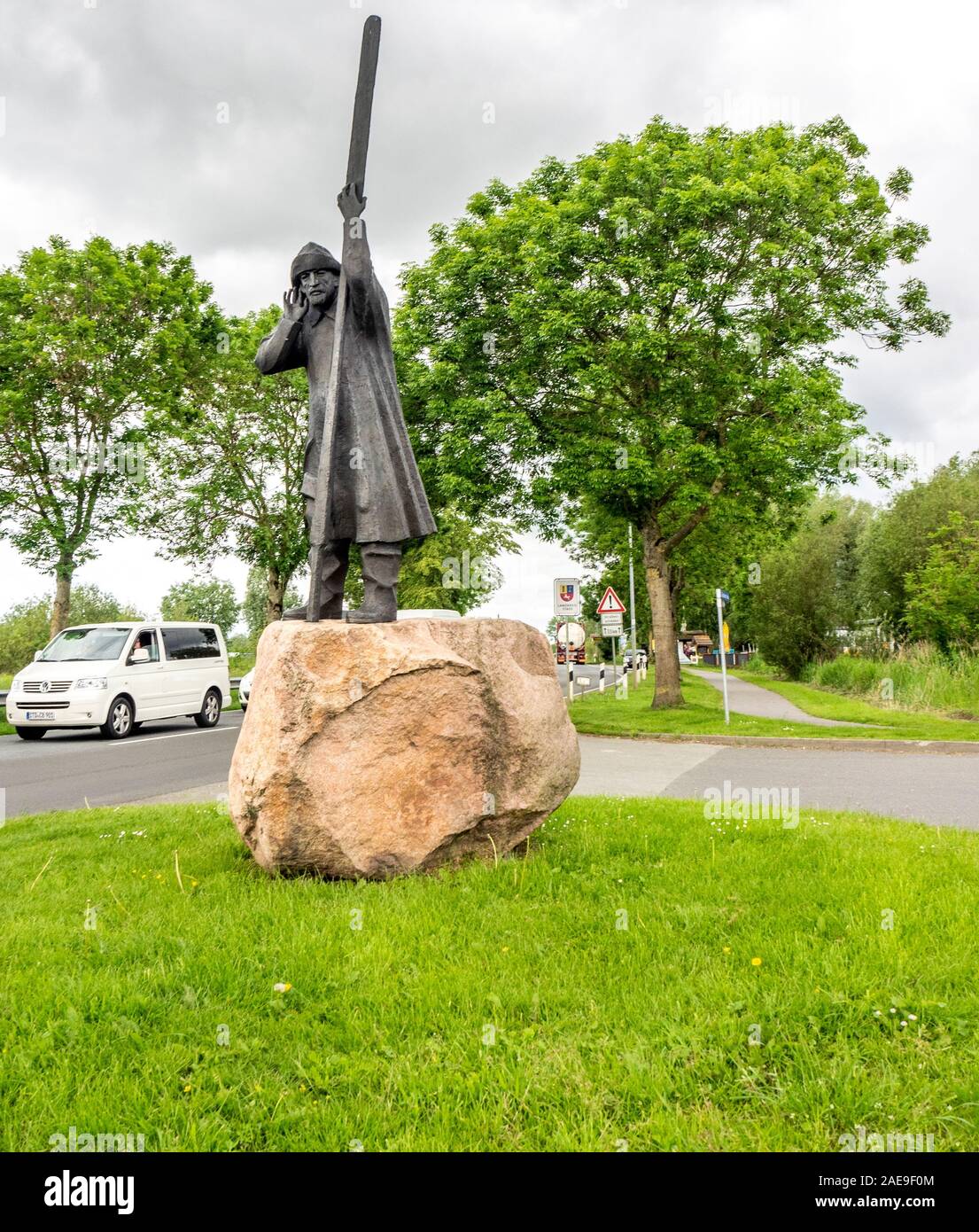 Bronzestatue eines Fährmanns auf einem Steinsockel des Bildhauers Frijo Müller-Belcke auf der Fähre Wischhafen – Glückstadt über Niedersachsen Stockfoto