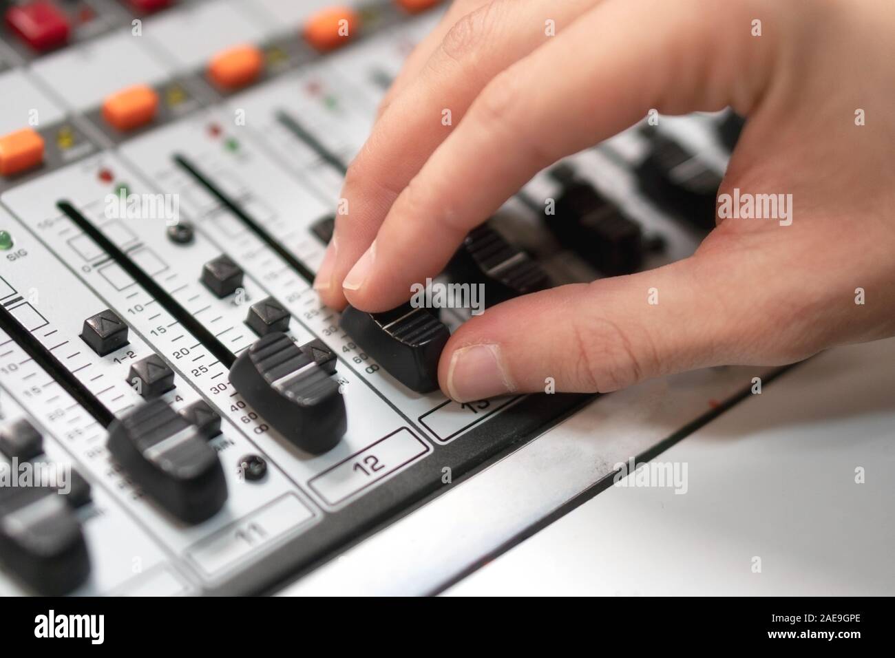Männliche Hand auf der Fader auf der Konsole. Sound Recording Studio Mischpult mit dem Ingenieur oder Musikproduzent. Stockfoto