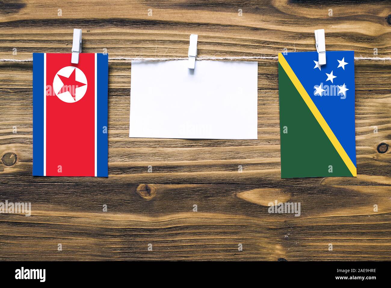 Hängenden Flaggen von Nordkorea und der Salomonen zu Seil mit wäscheklammer mit Kopie Raum befestigt auf weißem Papier auf Holz- Hintergrund. Diplomati Stockfoto