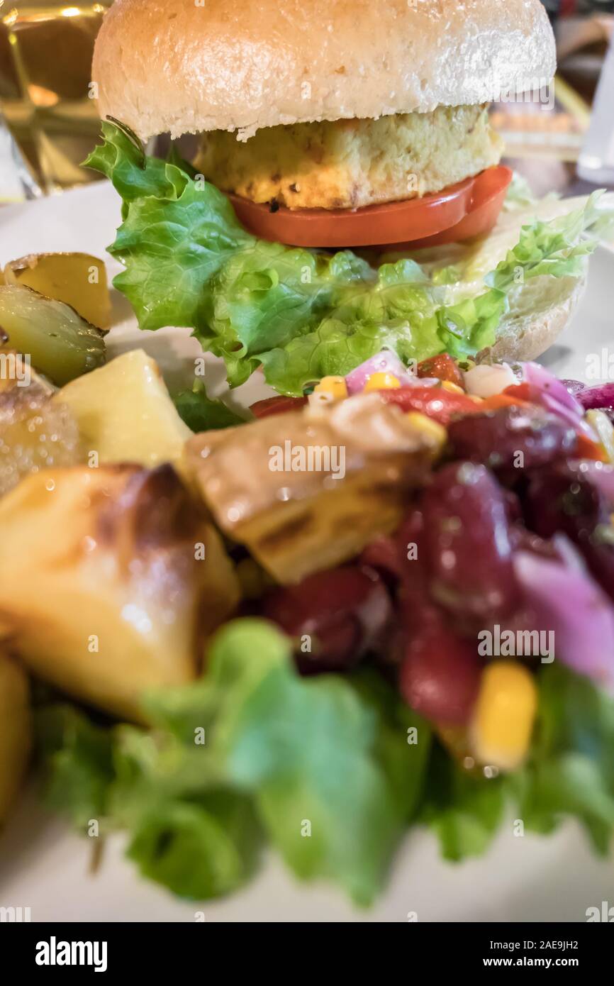 Gesunde vegane Burger mit Tomaten, gebackene Kartoffeln, Bohnen, Zwiebeln, Salat. Close-up. Stockfoto