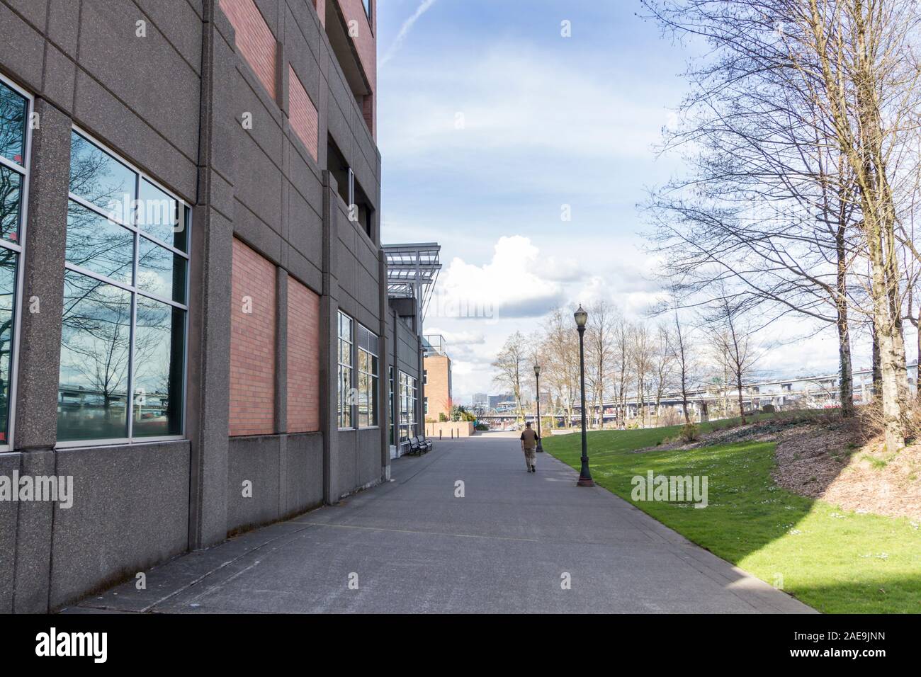 Eine Person, die zu Fuß auf dem Gehweg direkt neben einem Gebäude in Portland, Oregon. Stockfoto