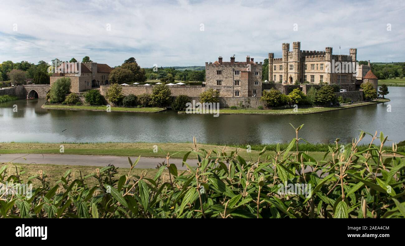 Panoramablick auf Schloss Leeds, mit dem Burggraben, Wanderweg und grünen Pflanzen im Vordergrund. Blauer Himmel und weiße Wolken. Keine Menschen. Postkarte anzeigen. Stockfoto