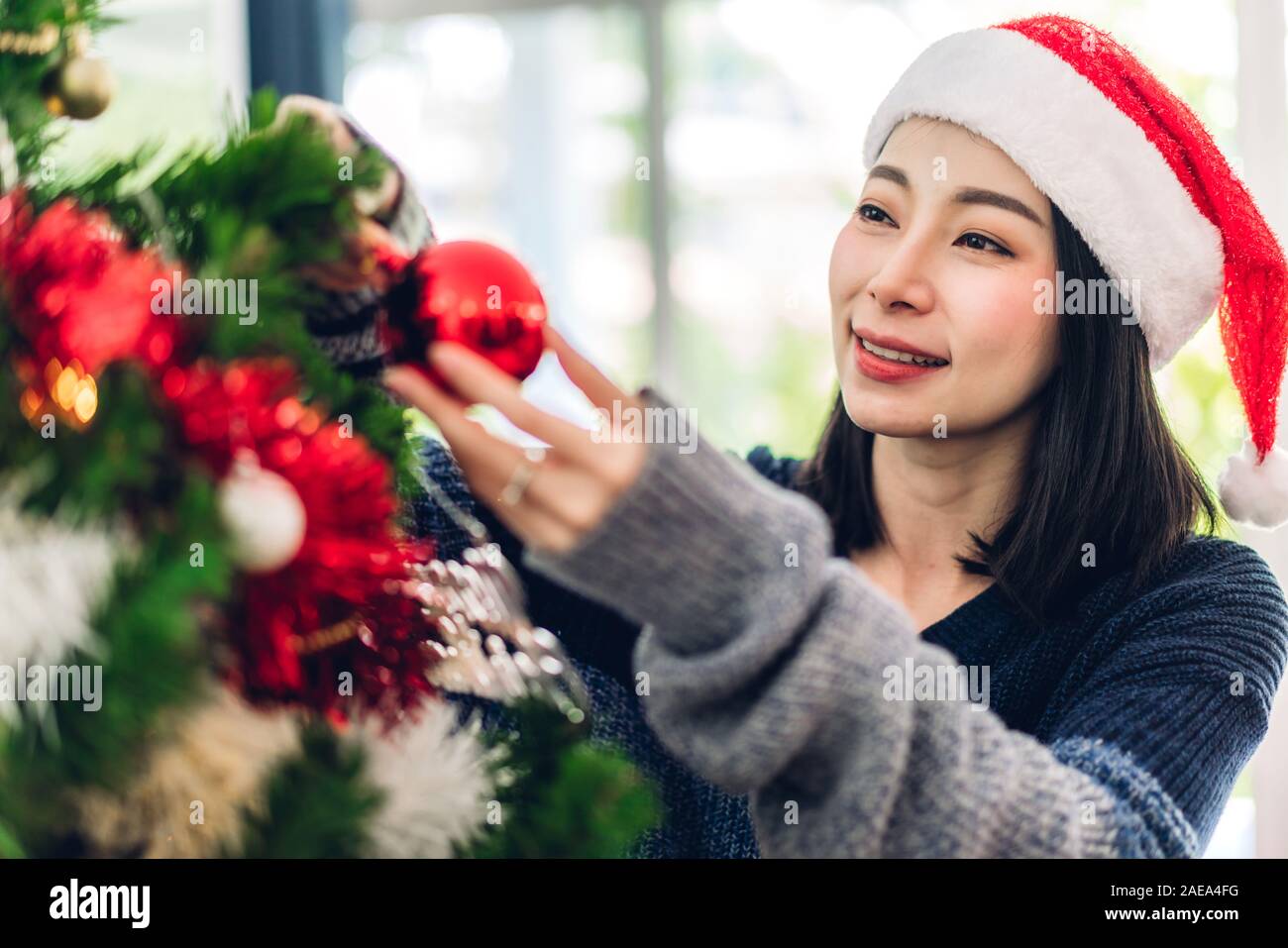 Asien Frau in santa Hüte Spaß schmücken Weihnachtsbaum und lächelnd