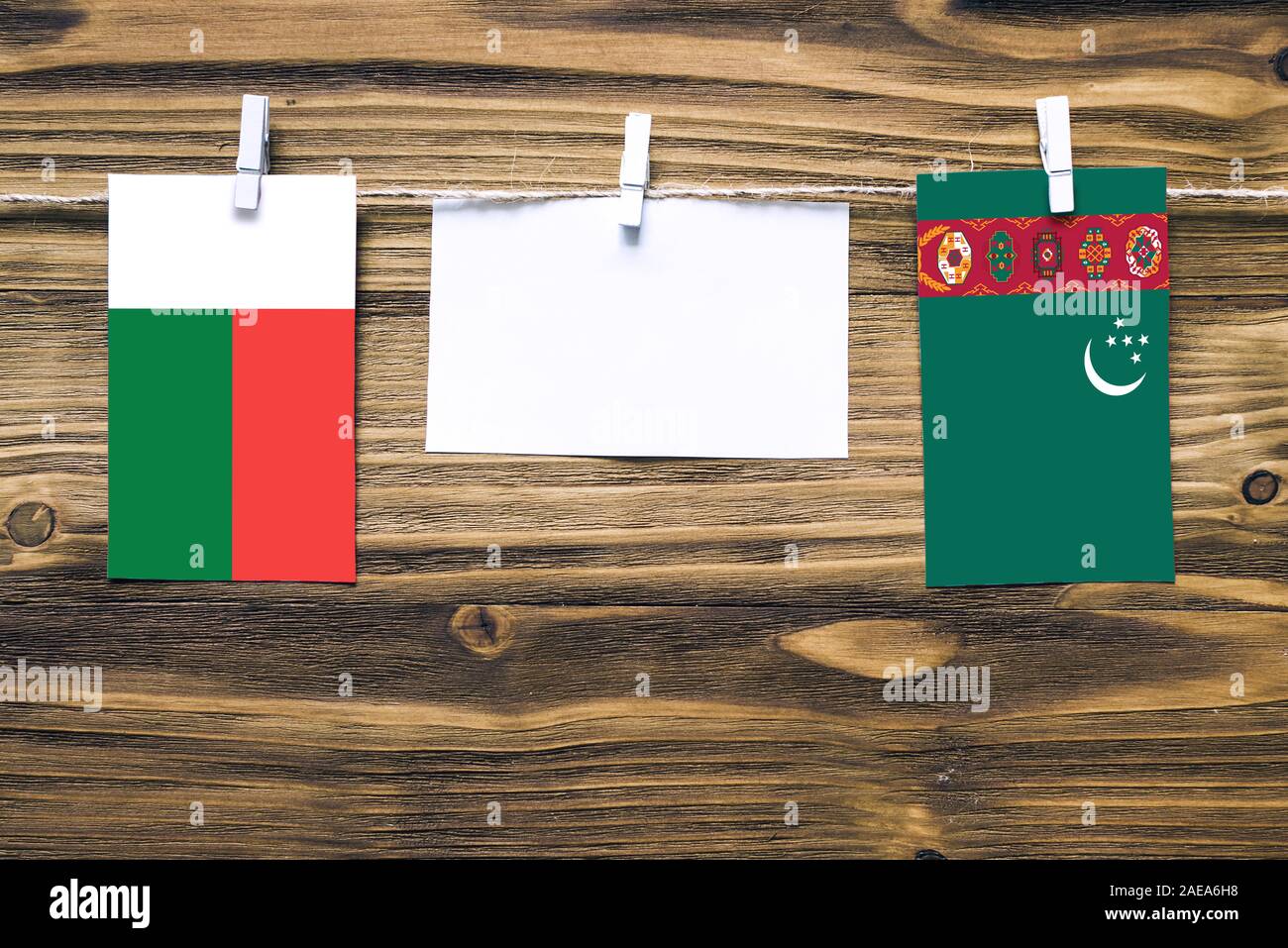 Hängenden Flaggen von Madagaskar und Turkmenistan zu Seil mit wäscheklammer mit Kopie Raum befestigt auf weißem Papier auf Holz- Hintergrund. Diplomatischen re Stockfoto