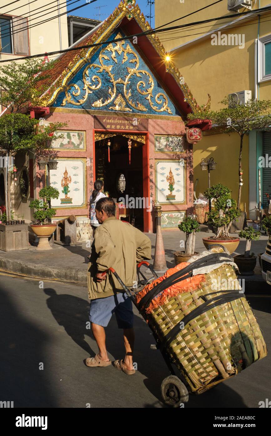 Ein Portier an Yodpiman Blumenmarkt bei Pak Klong Talaat, Bangkok, Thailand, führt eine kleine taoistische Tempel auf den Markt angeschlossen Stockfoto