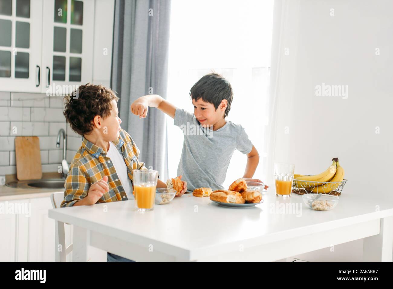 Zwei Geschwister tween Jungen echten Brüder am Frühstückstisch auf helle Küche Kampf an der Home Stockfoto