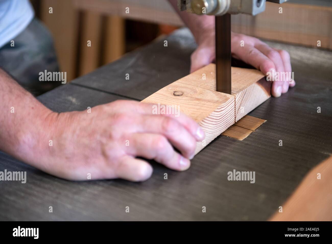 Tischler schneiden ein Stück Holz auf einer Bandsäge in Nahaufnahme auf seine Hände, als er Werke Stockfoto