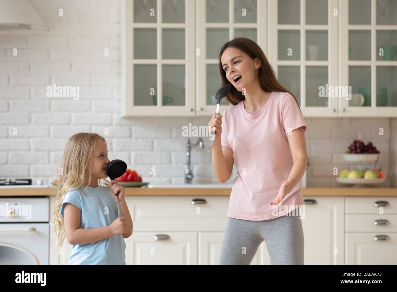 Mutter tanzen mit Tochter Holding suppenkelle wie Mikrofon singen Stockfoto