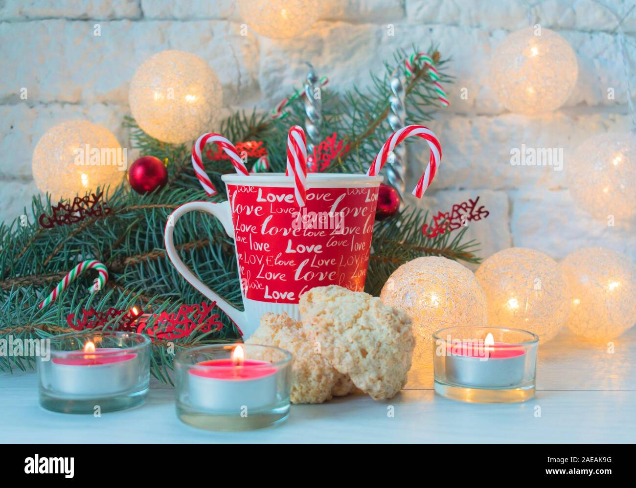 Eine Tasse Milch mit Weihnachten Bonbons und Kokosnuss cookies auf dem Hintergrund der Weihnachtsdekorationen. Stockfoto