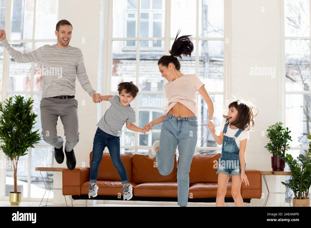 Glückliche Familie mit zwei Kindern zu Hause springen. Stockfoto