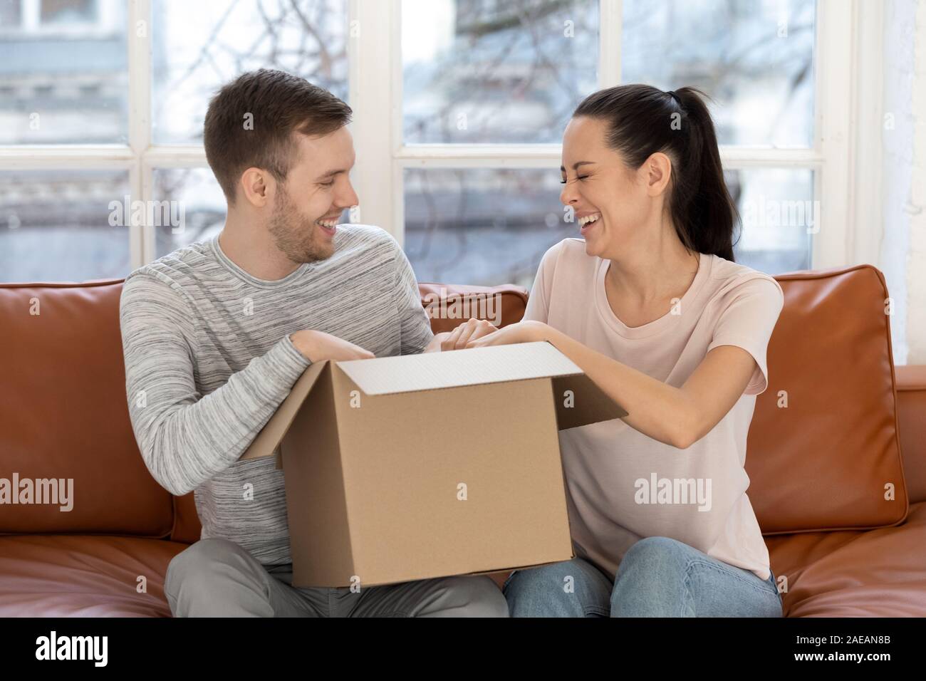 Glücklich lachend Paar öffnen Karton auf dem Sofa. Stockfoto