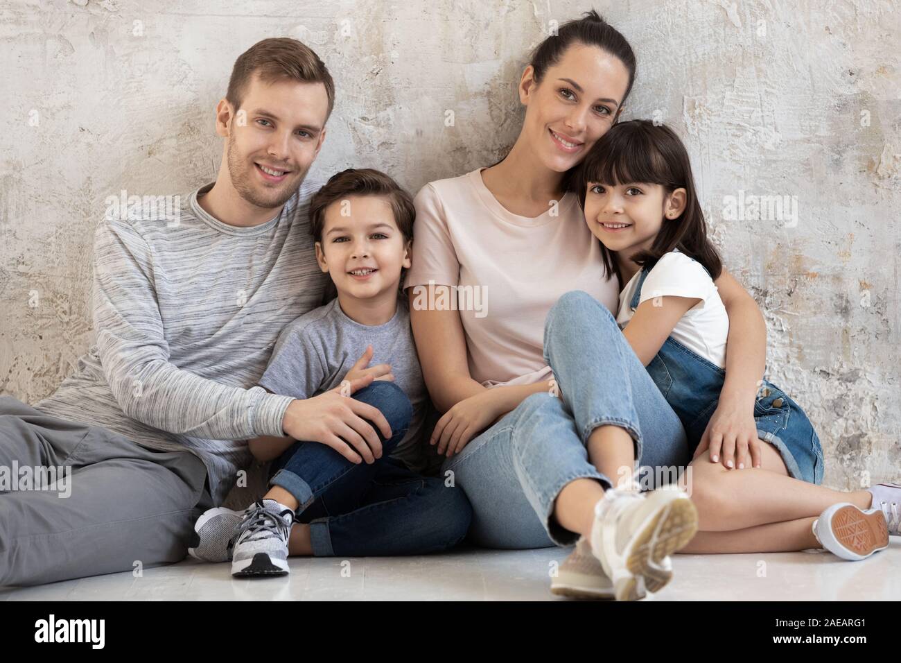 Portrait der glücklichen Familie mit zwei Kindern auf grauem Hintergrund. Stockfoto