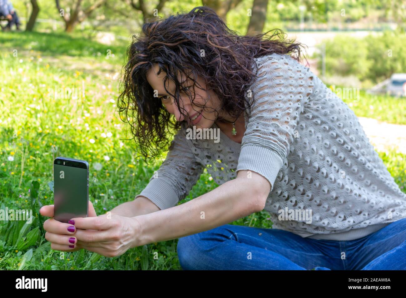 Junge Frau ein Foto an eine Blume mit iphone Stockfoto