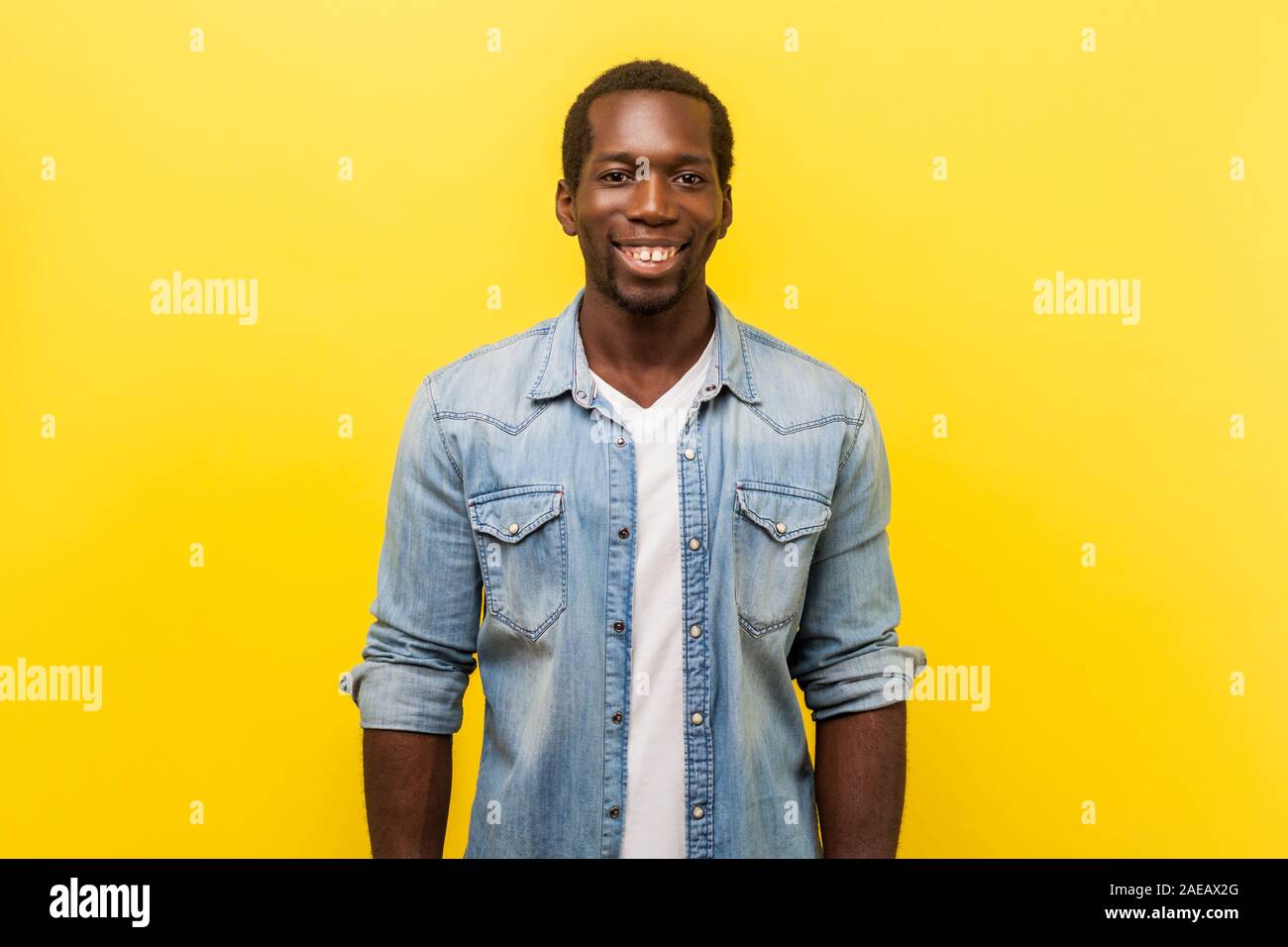 Portrait von fröhlichen stattlicher Mann in Jeans Shirt mit aufgerollten Ärmeln an Kamera suchen mit weißen toothy Lächeln, erfolgreiche Freiberufler oder Arbeitnehmer. Stockfoto