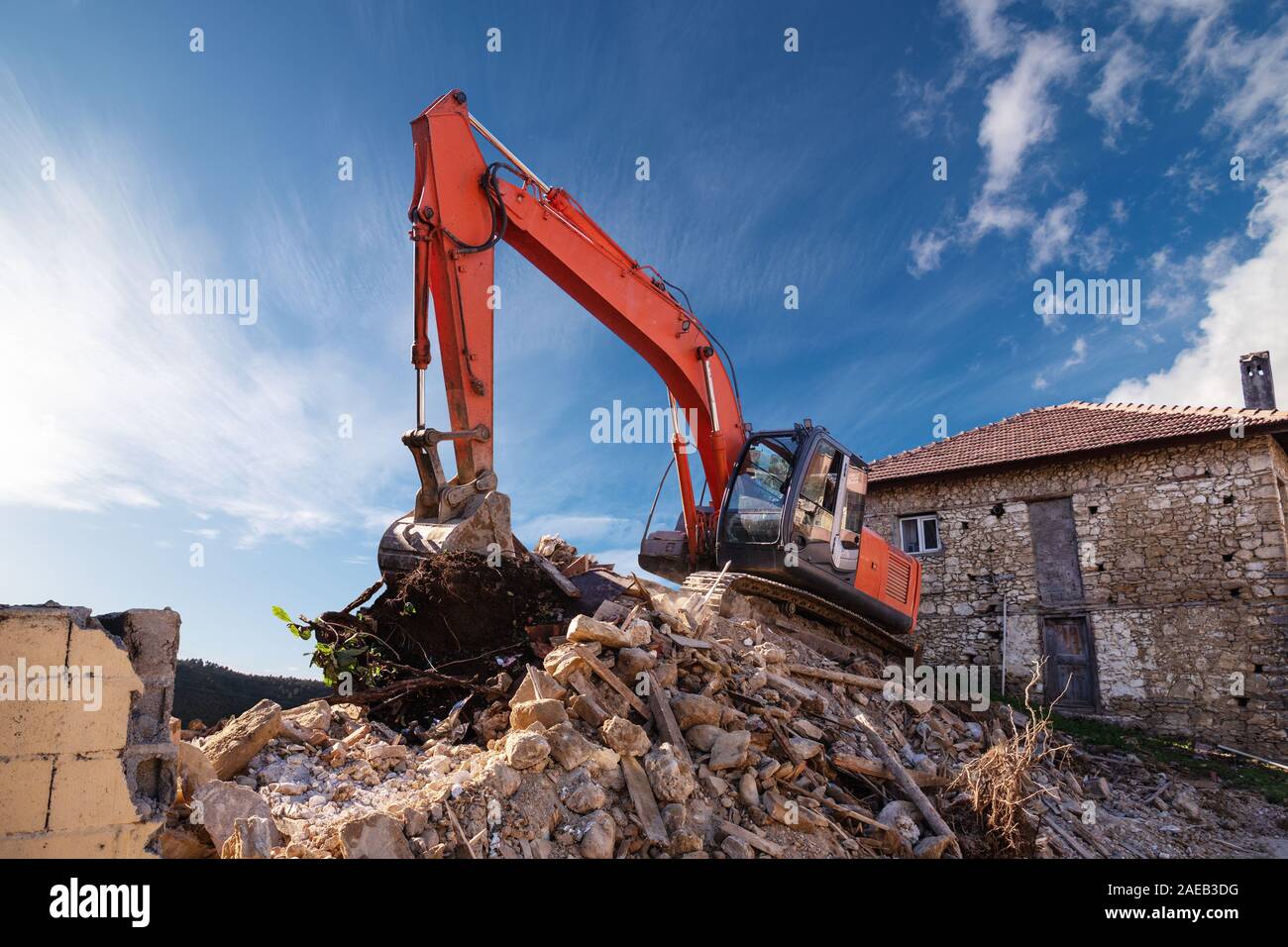 Eine schwere industrielle Arbeit Maschine, Digger ist die Zerstörung einer verlassenen, alten Gebäude. Stockfoto