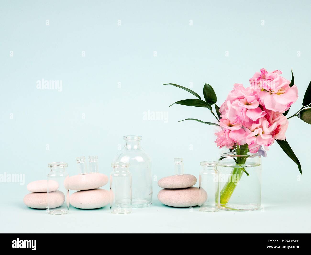 Rosa Blumen in einer Vase, neben den Zen-Steinen, Röhren von Ölen, das Thema Spa und Entspannung Stockfoto