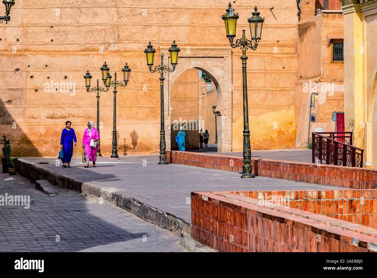 Die Menschen in der alten Stadt von Marrakesch wandern unter den großen alten Mauern und historischen Gebäuden. Stockfoto