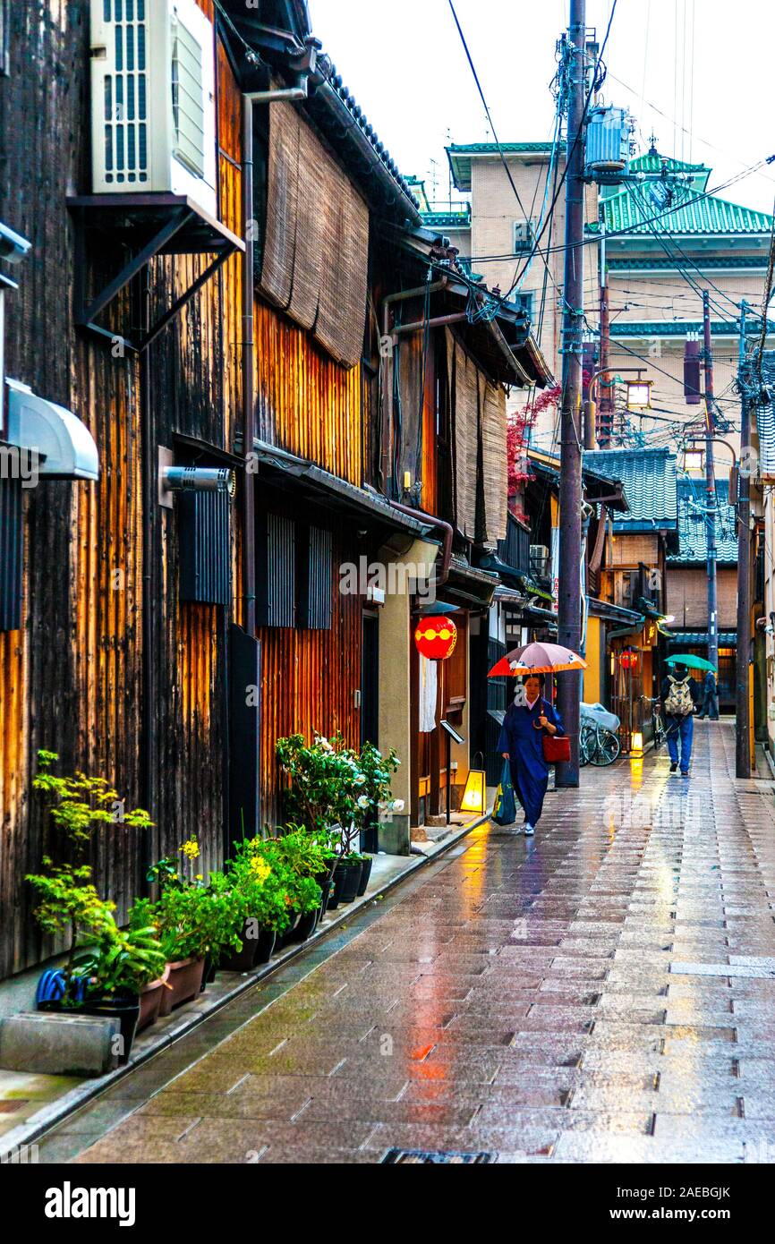 Ein regnerischer Tag in Kyoto, Menschen mit Sonnenschirmen, die eine Straße im Gion Geisha Distrikt, Japan, entlang laufen Stockfoto