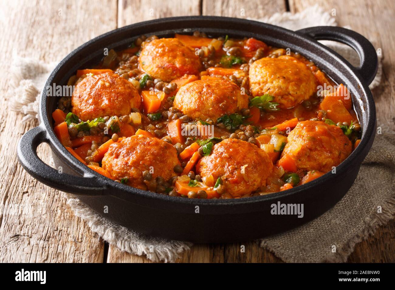 Würzige Frikadellen mit Linsen garnieren in Tomatensoße close-up in einer Pfanne auf dem Tisch. Horizontale Stockfoto
