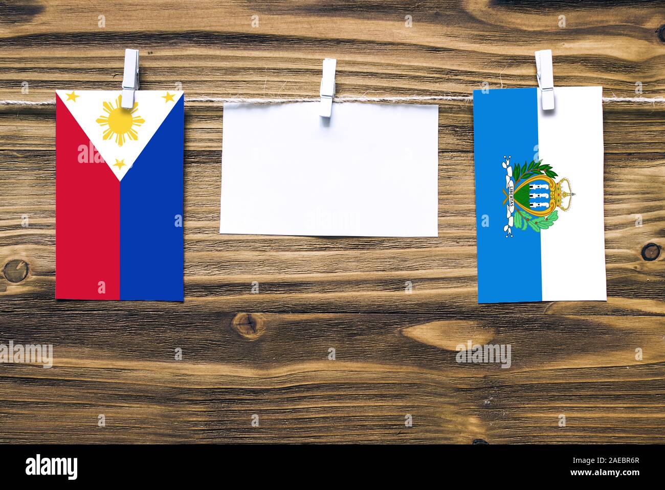 Hängende Fahnen der Philippinen und San Marino zu Seil mit wäscheklammer mit Kopie Raum befestigt auf weißem Papier auf Holz- Hintergrund. Diplomatischen rel Stockfoto
