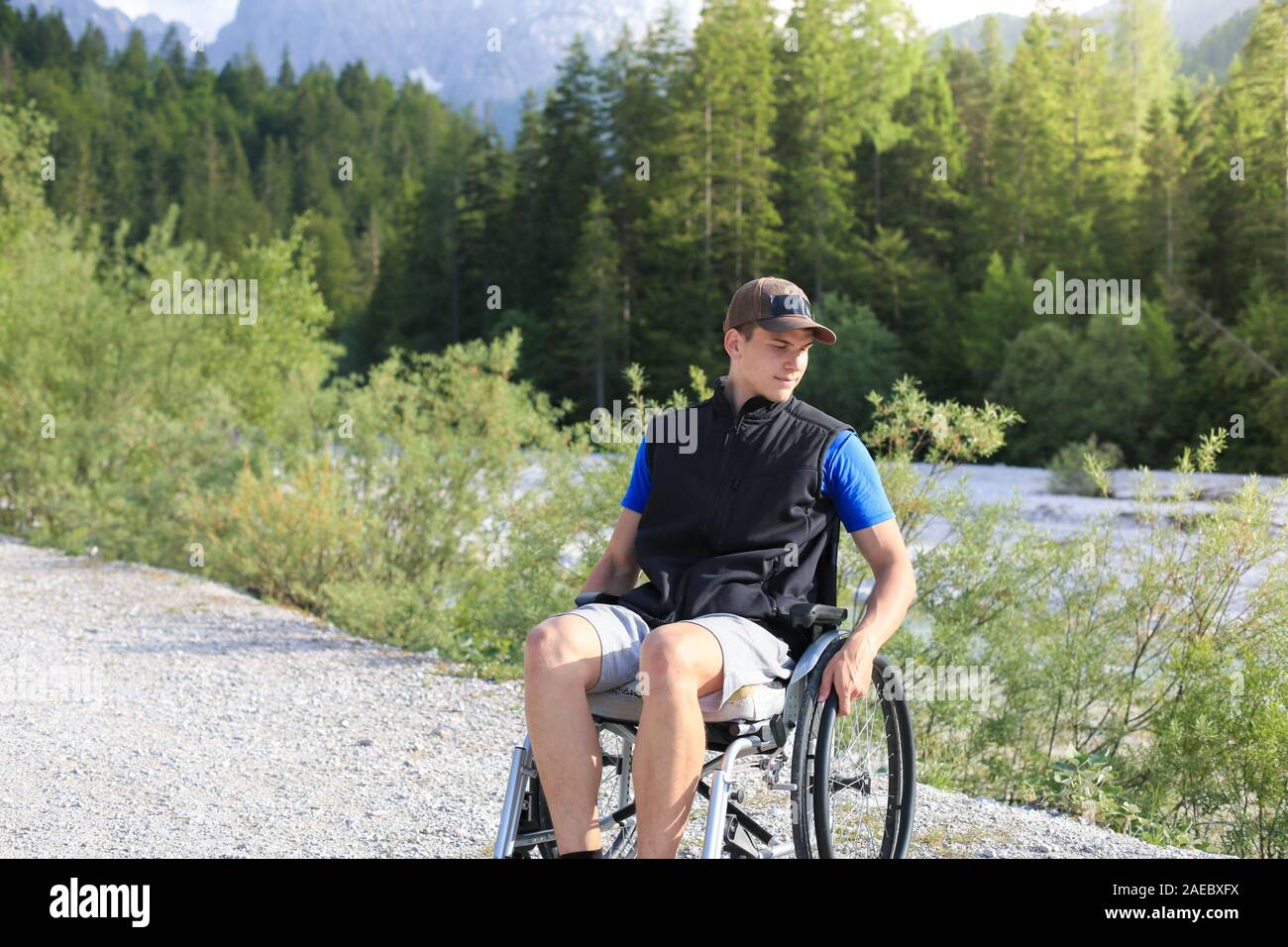 Glückliche junge Mann im Rollstuhl in der freien Natur an einem sonnigen Sommertag Stockfoto