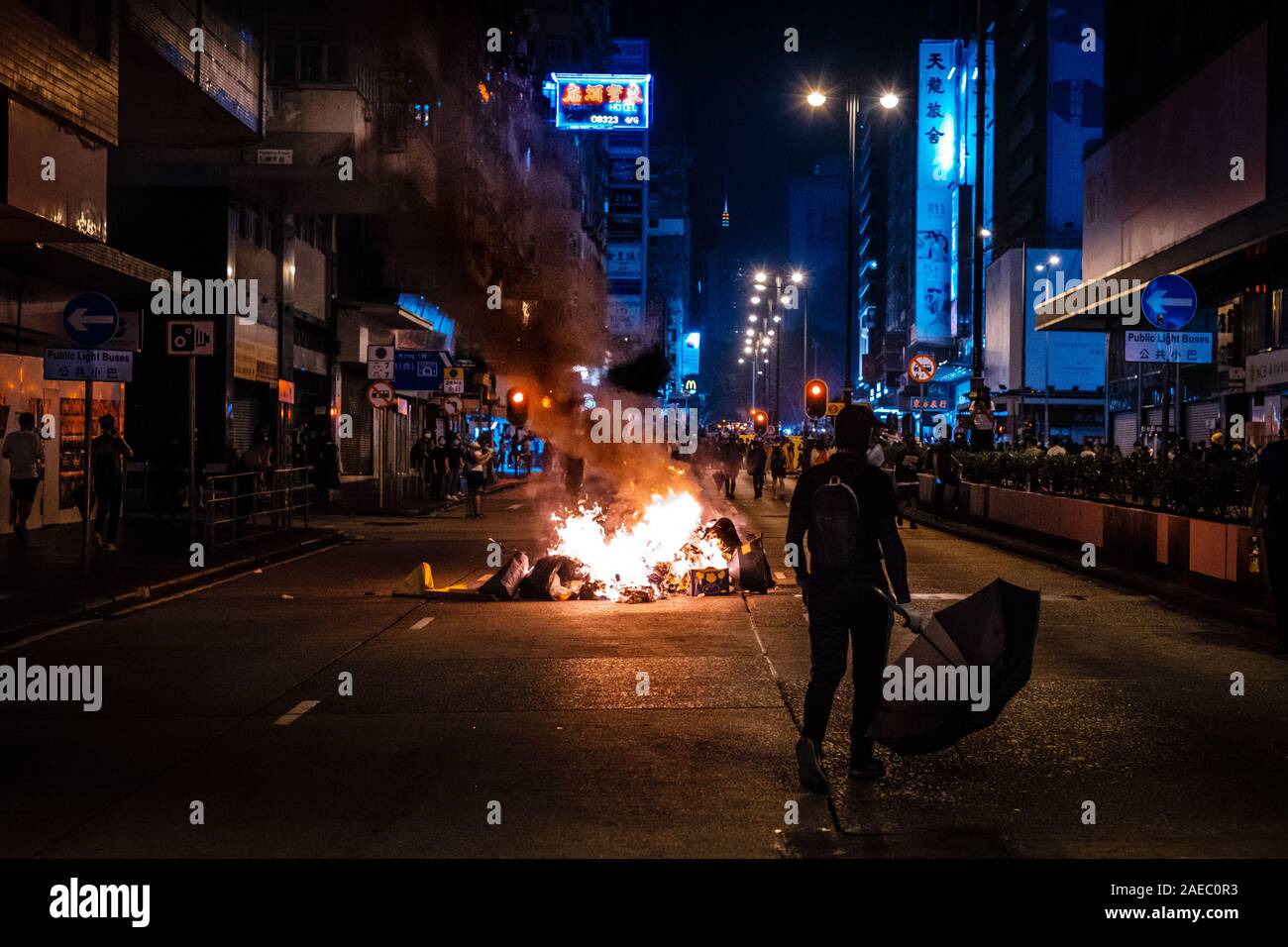 HongKong - November 17, 2019: Maskierter Demonstrant mit Regenschirm bei Feuer, als Straße Barrikade während der 2019 HongKong Proteste verwendet Stockfoto